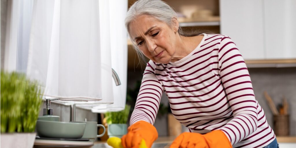 senior woman with ocd obsessively cleaning kitchen