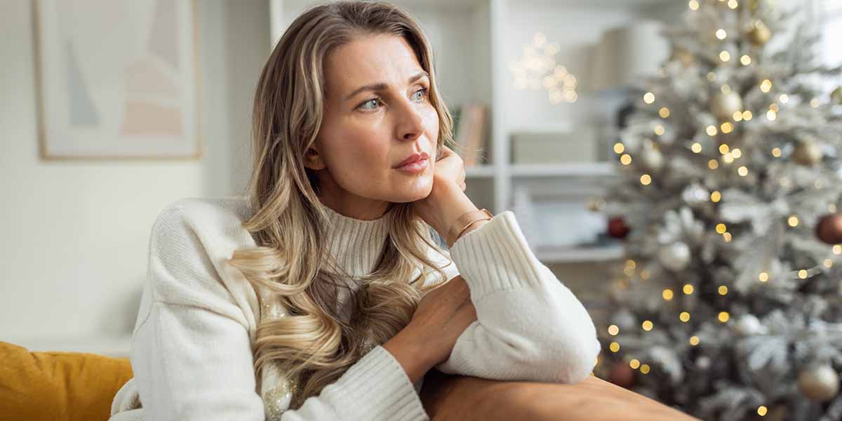 woman sits next to christmas tree