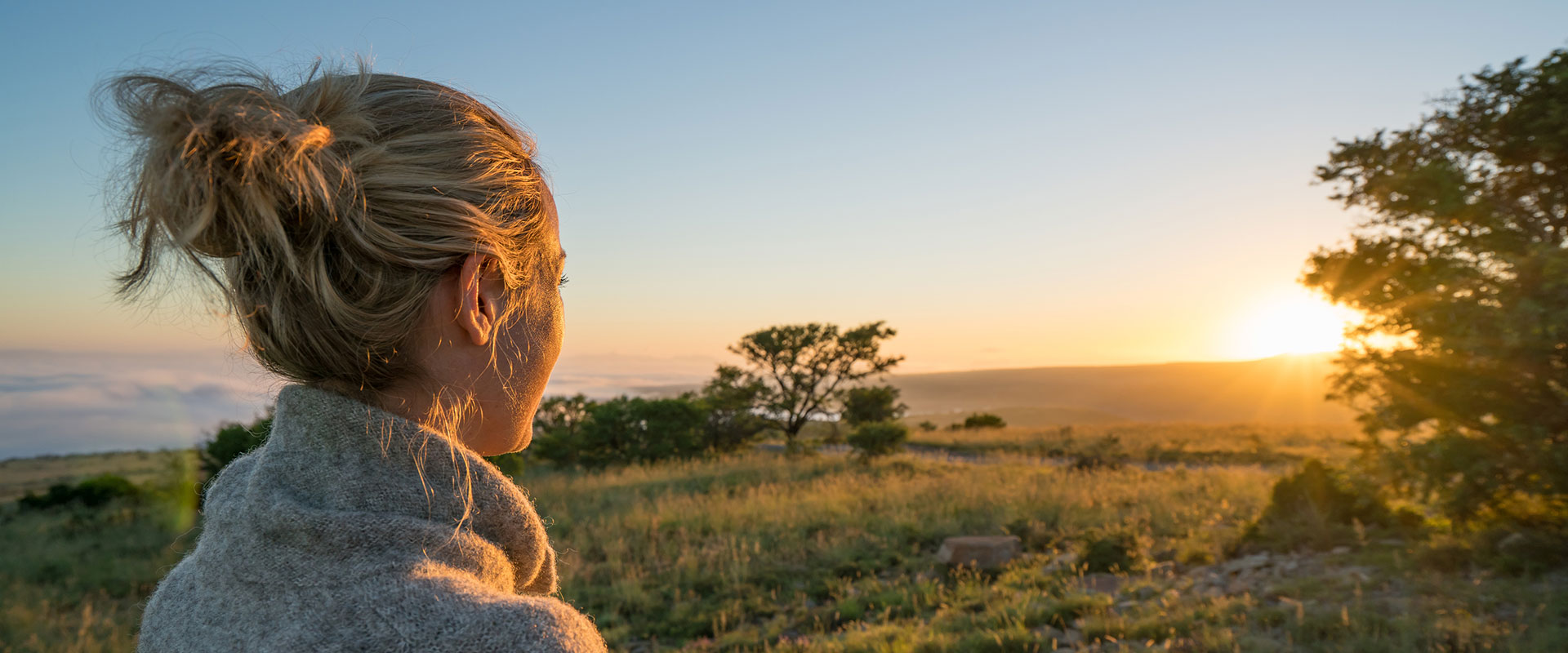 One young woman looking at sun rising in the savannah, Mountain Zebra national park in South Africa.