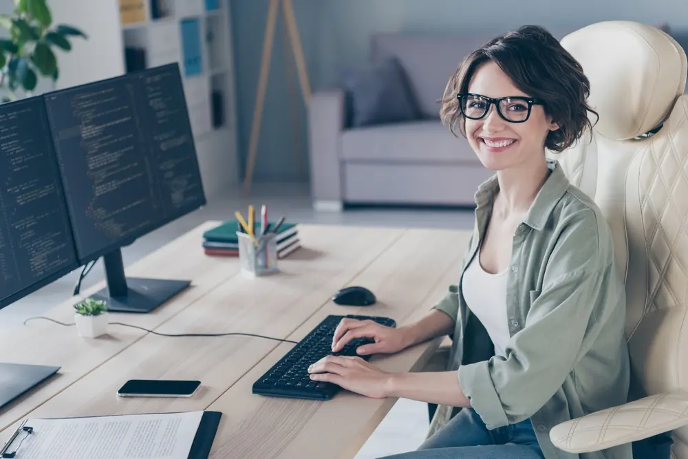 young woman with glasses smiling while working on computer
